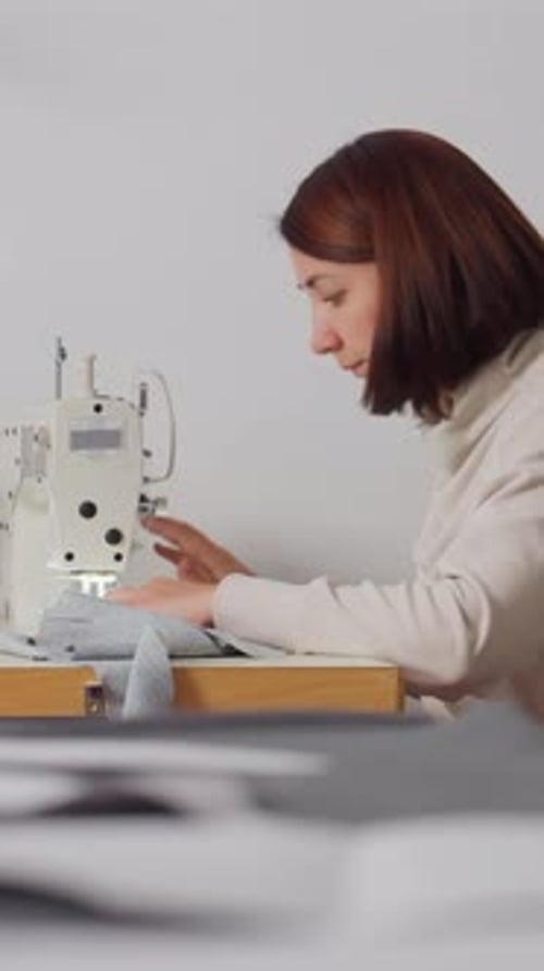 Une artisane répare soigneusement le tissu et répare artistiquement le tissu dans un atelier de couture silencieux