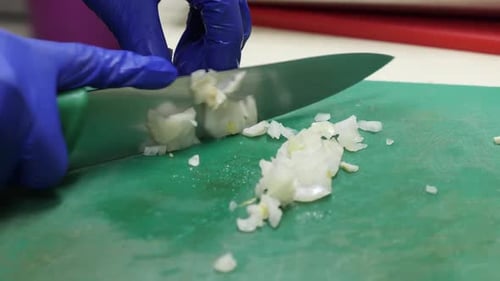 Chef Gloves Chopping Onion on Cutting Board