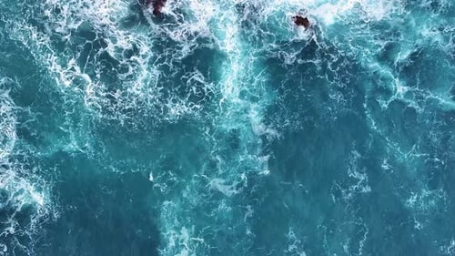 View of waves crashing against rocks in vibrant blue ocean waters