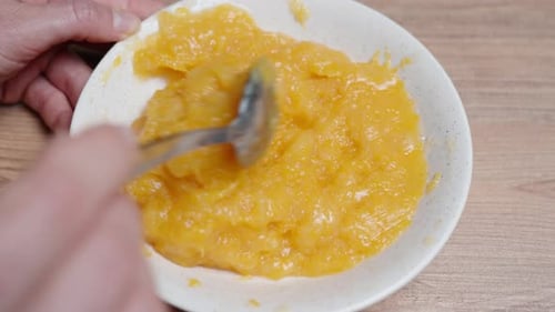 D'en haut, une femme remue la garniture à la compote d'orange pour le gâteau.