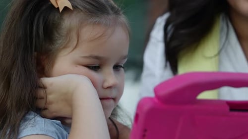 Young Child Engaged with Colorful Device During Outdoor Playtime