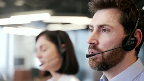 Close up of head of smiling male customer service representatives with headsets working in modern