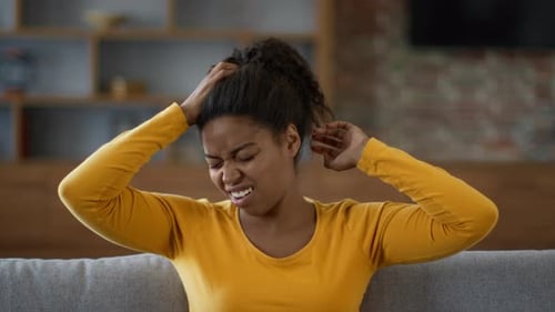 Woman sitting on couch and scratching her head