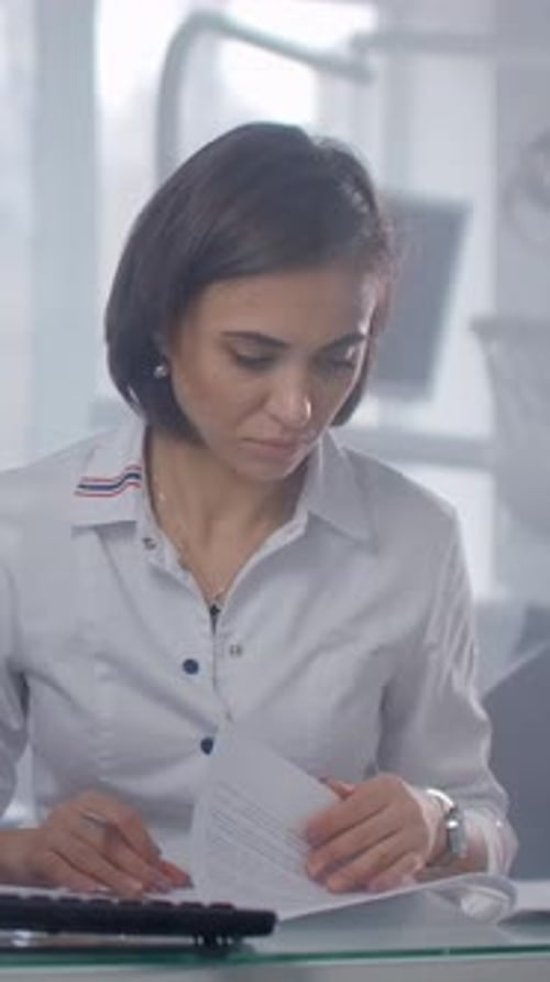 Femme médecin concentrée travaillant au bureau médical examinant les documents des patients et utilisant un ordinateur