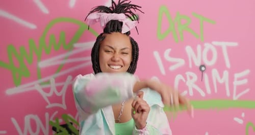 Trendy Young Woman Dancing with Lollipop in Studio
