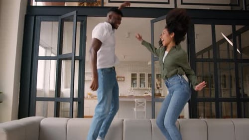 Excited Couple Dancing on Sofa Indoors