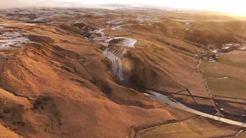 Aerial view of Skógafoss waterfall and Iceland's rugged natural beauty at sunset