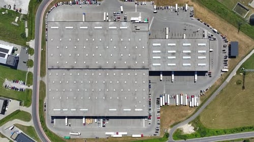 Operaciones logísticas en un almacén bullicioso con furgonetas de reparto