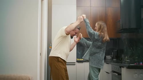 Joyful couple dancing and having fun together in the kitchen
