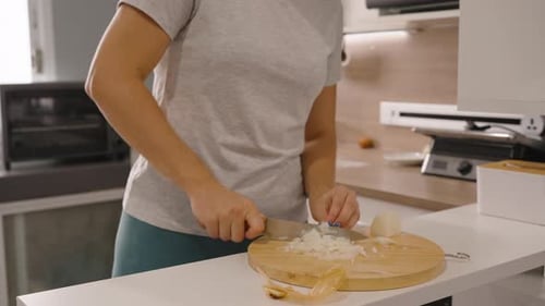 Woman Chopping Onion on Wooden Board in Kitchen