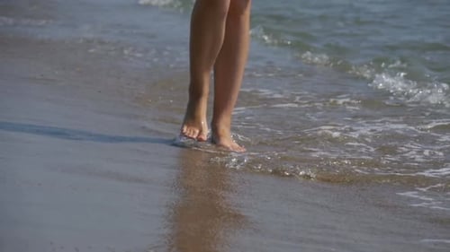 Young Girl Walks Along the Beach of the Sea Coast in Slow Motion