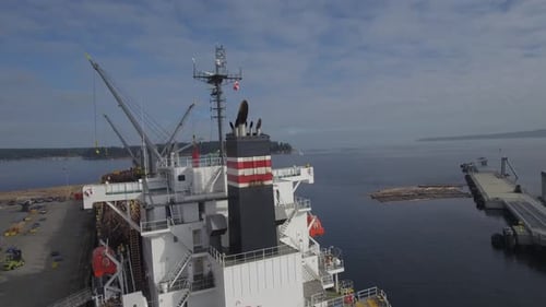 Imagens de drone em 4K de um grande navio branco sendo carregado com troncos