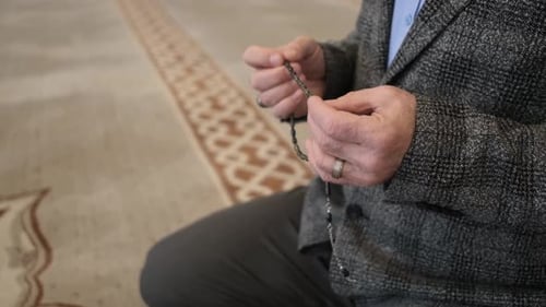 Adult Using Prayer Beads Indoors