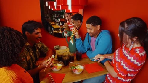 Happy multicultural friends eating and laughing in a restaurant