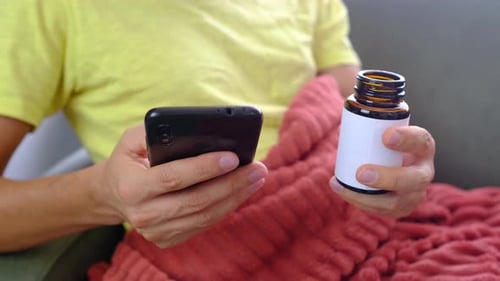 Man Holding Phone and Medicine Bottle