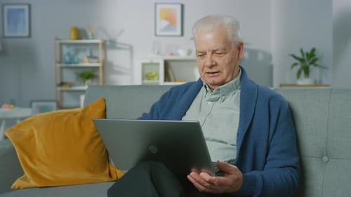 Senior Man Sitting and Using Laptop on Sofa