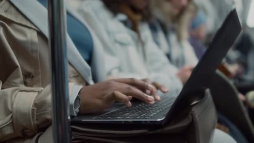 Anonymer freiberuflicher Mitarbeiter, der im öffentlichen Verkehr auf einem Laptop tippt