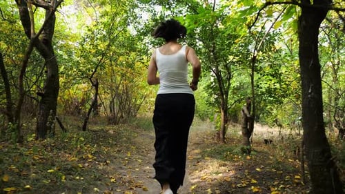 Adult Brunette Woman Running Along Path at Summer Forest Lady Jogging Among Trail at Wild Nature