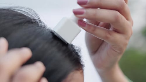 Woman Applies Product to Hair with Device Close Up