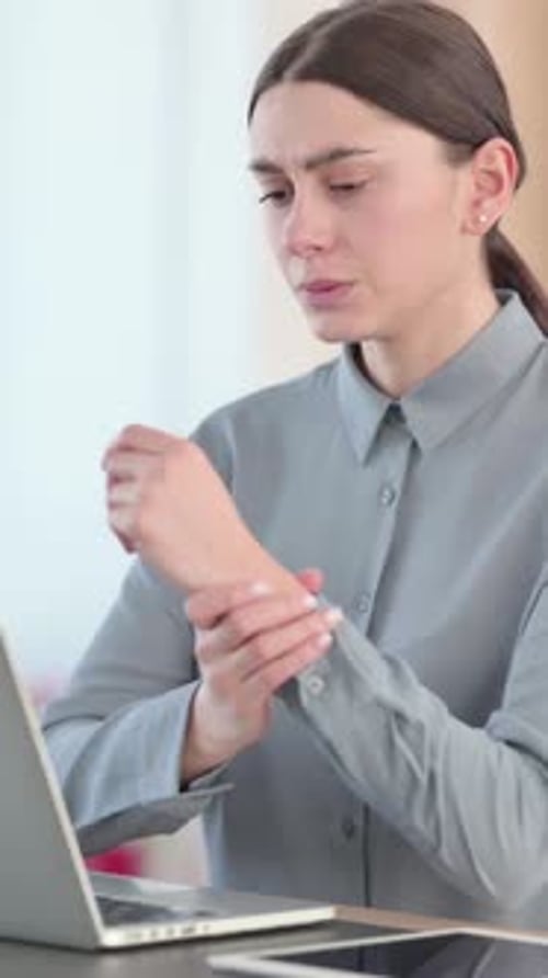 Woman with Wrist Pain Massaging Sore Joint at Desk