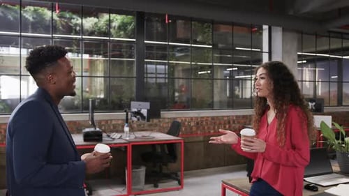 Two happy diverse creative colleagues in discussion in casual office, slow motion