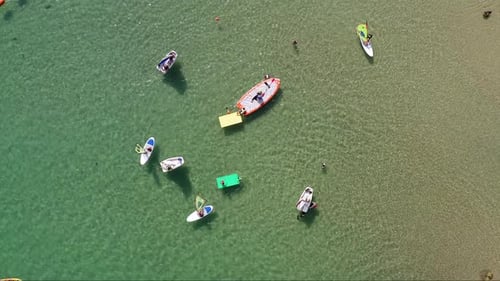 People on various colourful floating Mats and small boats at the Beach