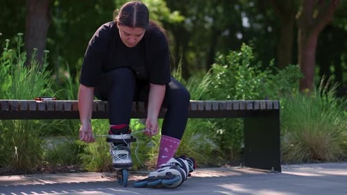 young hipster girl puts on roller skates in skate park before starting skating street extreme sport
