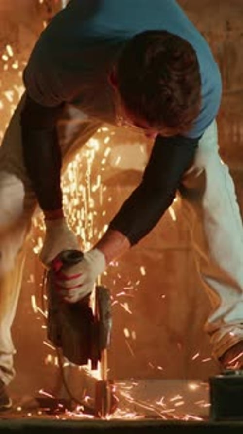 A Skilled Worker Cutting Metal with a Grinder Sparks Flying Amidst a Dimly Lit Workshop