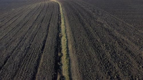 Flying Over Large Plowed Field of Black Soil Field of Dug Up Earth on Autumn Day