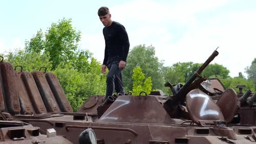 Young Adult Standing on Damaged Military Tank