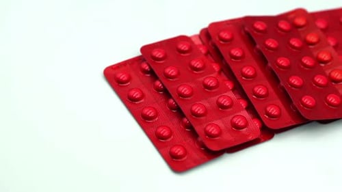 Vibrant Red Pills in Blister Packs on White