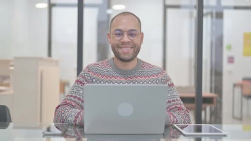Young Adult Smiling in Office with Laptop