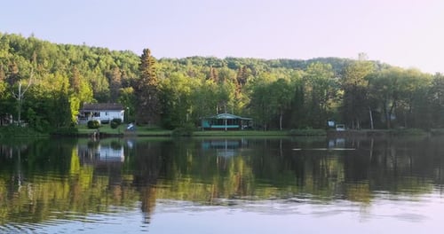 Stunning static shot of cottage houses on a calm river in Quebec, Canada.