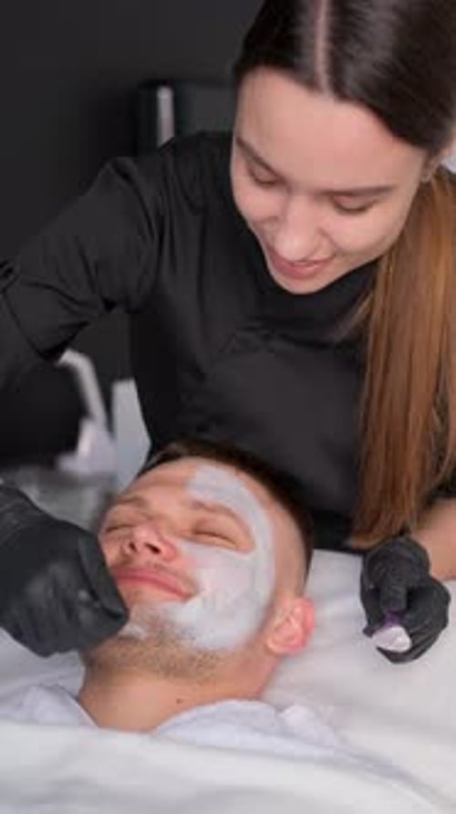 Esthetician Applying Facial Mask to Man at Spa
