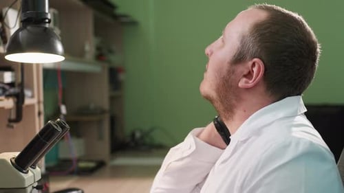Man in Lab Coat Using Microscope