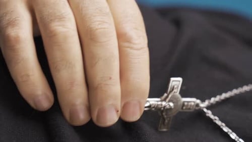 Vertical Video of Religious christian man with white beard hangs cross necklace around his neck.
