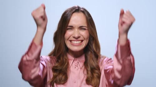 Excited businesswoman celebrates success with yes gesture and clapping in studio