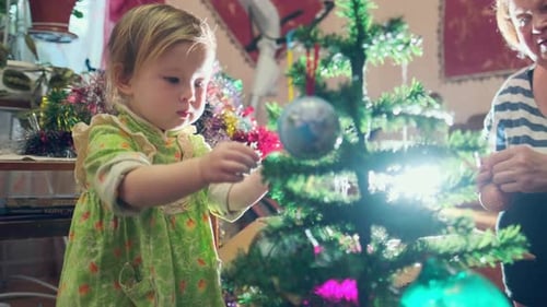 Child Decorating Christmas Tree with Family Indoors