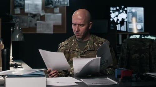 Serious Commander Reviewing Documents in Central Intelligence Hub