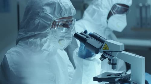 Female Lab Scientist in Protective Uniform Examining Blood under Microscope