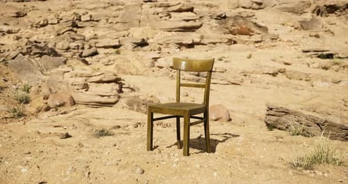 Lonely Chair Placed Amidst Rocky Desert Landscape Under Clear Blue Sky