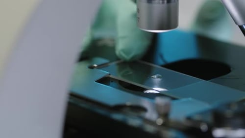 Unrecognizable Scientist Examining Drop under Microscope