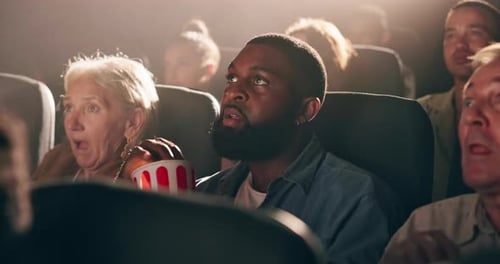 People, movie and fear with popcorn in theater with snack in crowd, thinking and relax in night