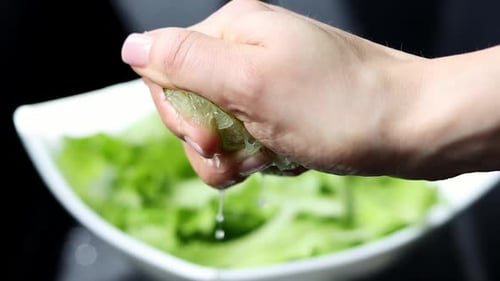 Splash of lime juice close up in slow motion. Hand squeezing half of a fresh lime