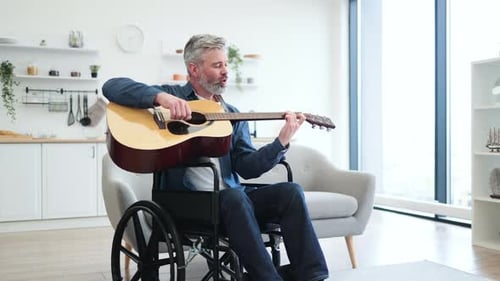 Man in wheelchair plays guitar and sings indoors