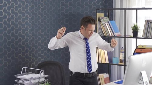 Joyeux homme d'affaires célébrant le fait de s'asseoir au bureau et de travailler sur un ordinateur les bras levés.