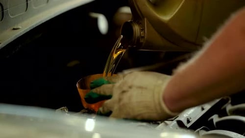 An Auto Mechanic Pours New Oil Into an Engine at a Service Center