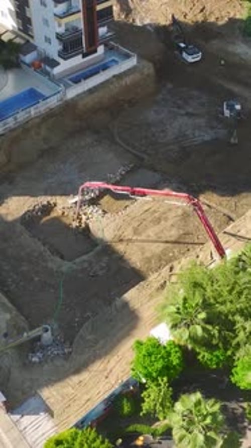 Vídeo vertical: sitio de construcción ocupado con trabajadores y equipo pesado