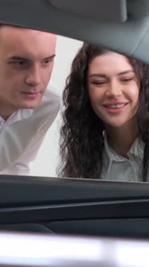 A Happy Young Family Buys a Luxury Car Car Sales Manager Showing a New Car Vertical Video