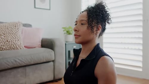 Mulher afro-americana com o braço direito estendido, torso giratório, estendendo a mão na sala de estar, se alongando